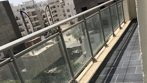 A balcony with a glass railing overlooking a residential area with buildings and greenery. - Superb Mont Carlo Hamam Sousse vacation apartment (Hammam Sousse)