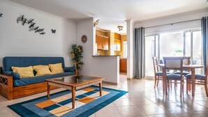 Een woonkamer met een bank, salontafel en uitzicht op de keuken.