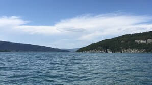 Ruhige See unter einem klaren Himmel, in der Ferne Hügel.