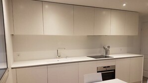 Eine moderne Küche mit weißen Schränken, einem eingebauten Backofen und einem Spülbecken.