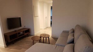 Ein Wohnzimmer mit einer Couch, einem Fernseher und einem kleinen Tisch.