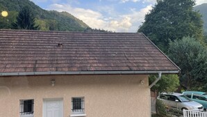 Un edificio de una sola planta con techo inclinado, una puerta blanca y dos ventanas con rejas.