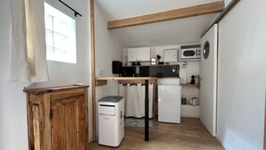 Une cuisine compacte avec des poutres en bois, un réfrigérateur, un four à micro-ondes et un petit évier.