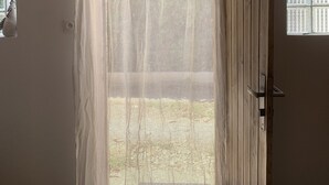 Une pièce avec une porte en bois, une fenêtre à carreaux et un rideau léger.