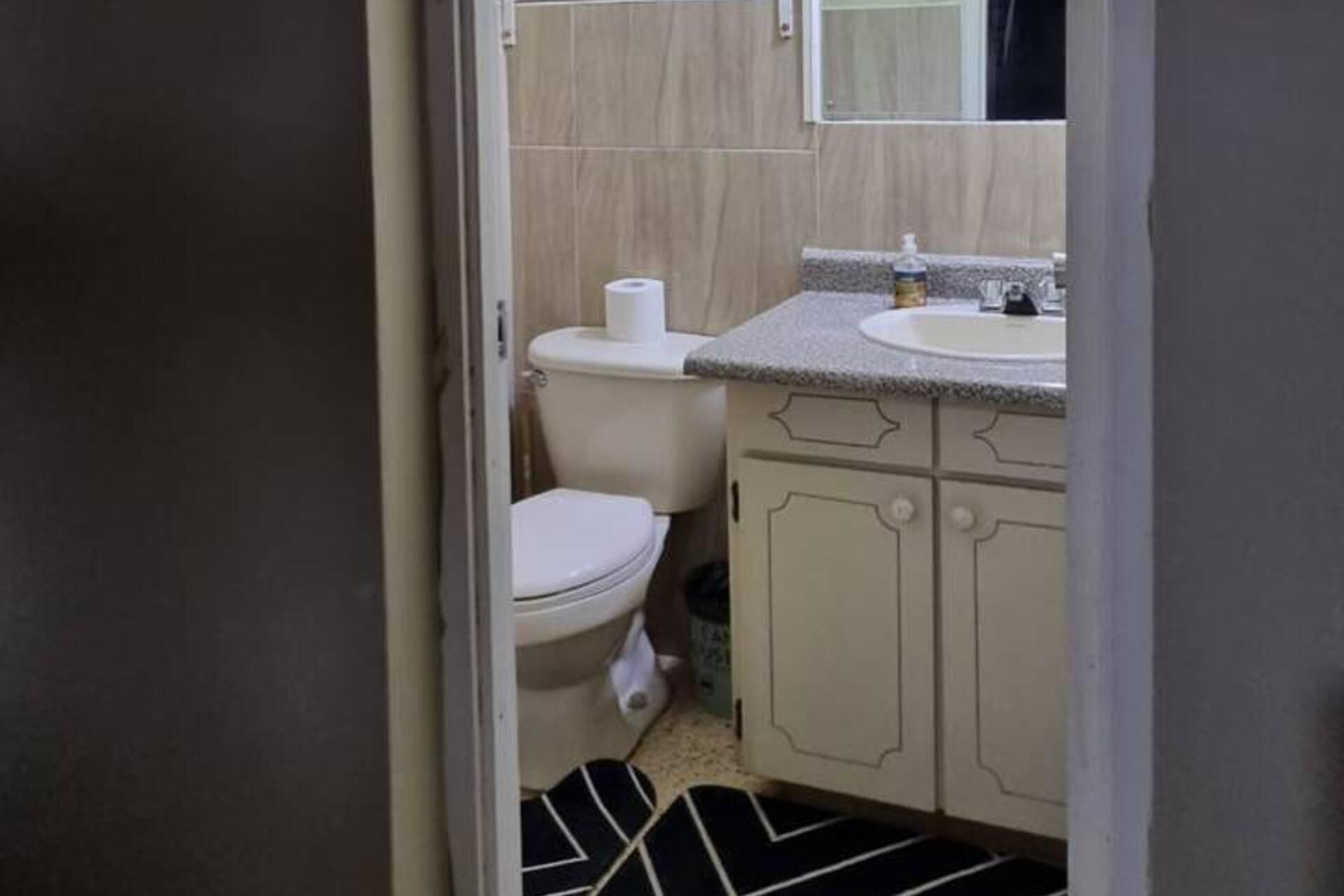 A small bathroom with a toilet, sink, and cabinets.