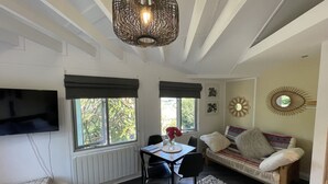 Una sala de estar acogedora con televisor, una mesa de comedor con sillas, un sofá y un espejo decorativo.