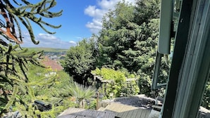 Un espacio al aire libre techado con mesas de picnic de madera y vistas a un paisaje verde.