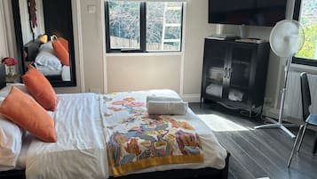 Une chambre à coucher avec un lit, une télévision, un ventilateur et une fenêtre.