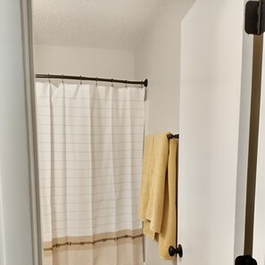 A bathroom with a shower curtain, a towel rack with towels, and a door. - Cheerful modern, minutes to beach (Nokomis)