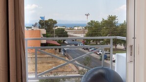 A balcony with a view of a road and buildings, a large exercise ball, and a curtain. - Modern apt.with sea view in Glyfada (Glyfada)