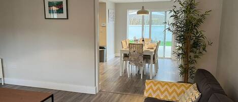 A living room with a sofa, a coffee table, and a dining area with chairs and a table.