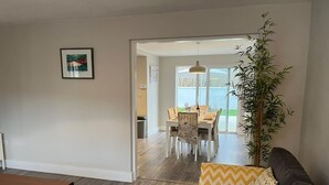 A modern living room with a dark brown sofa, a wooden coffee table, and a dining area with a table and chairs. - Bay Area House is a perfect base to tour Connemara (Spiddal)
