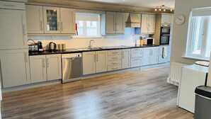 A modern kitchen with light-colored cabinets, stainless steel appliances, and a wooden floor. - Bay Area House is a perfect base to tour Connemara (Spiddal)