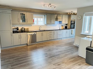 A modern kitchen with light-colored cabinets, a stainless steel dishwasher, and a window providing natural light.