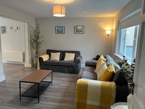 A living room with a sofa, a coffee table, a lamp, and a radiator.