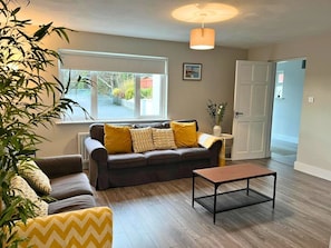 A living room with a sofa, armchairs, a coffee table, and a large window.