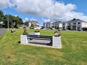 A grassy area with a bench, surrounded by residential buildings.