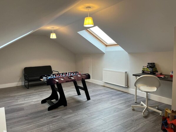 A room with a foosball table, a black chair, a white office chair, a skylight, and a radiator. - Bay Area House, Spiddal (Spiddal)
