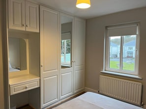 A bedroom with a built-in wardrobe, a bedside table, and a window with a view of the outside. - Bay Area House, Spiddal (Spiddal)