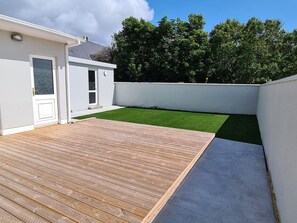 A modern residential property with a wooden deck, a small lawn, and a white exterior wall. - Bay Area House, Spiddal (Spiddal)