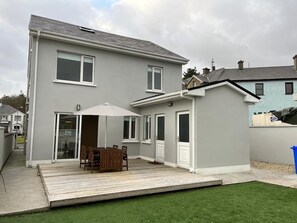 A two-story residential building with a patio area featuring a table and chairs, a covered seating area, and a small deck. - Bay Area House, Spiddal (Spiddal)
