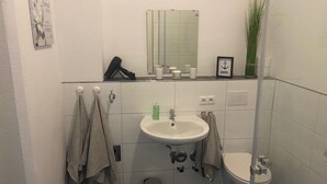Casa de banho com lavatório, espelho, toalheiro, sanita e lixeira.
