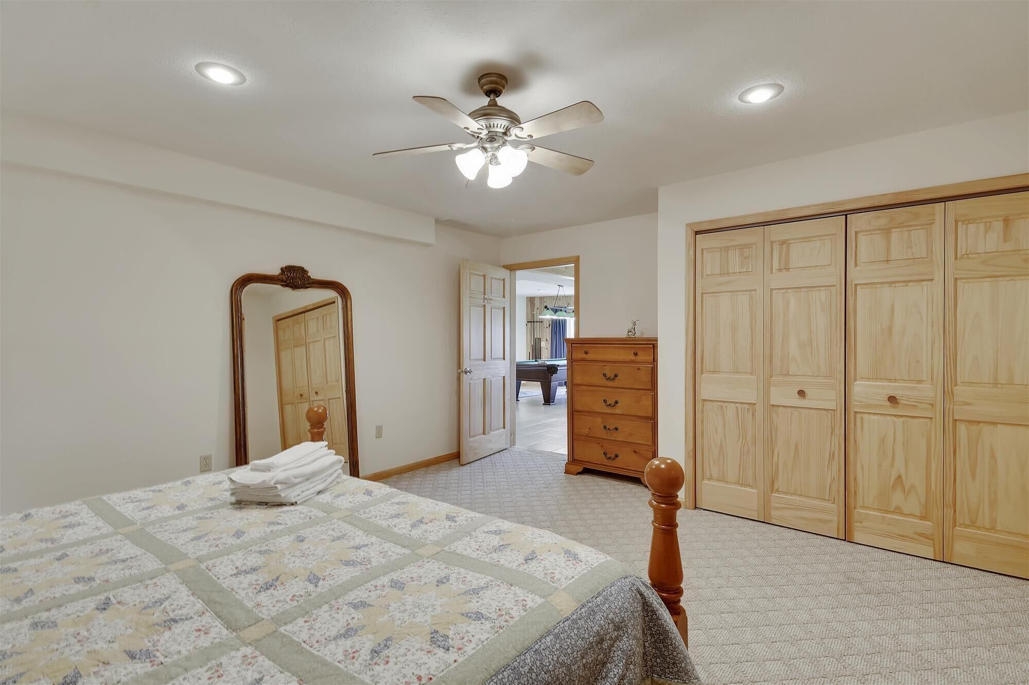 Un dormitorio con cama, cómoda, espejo y armario.