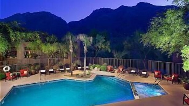 Ein Swimmingpool mit Liegestühlen und Blick auf die Berge in der Abenddämmerung.