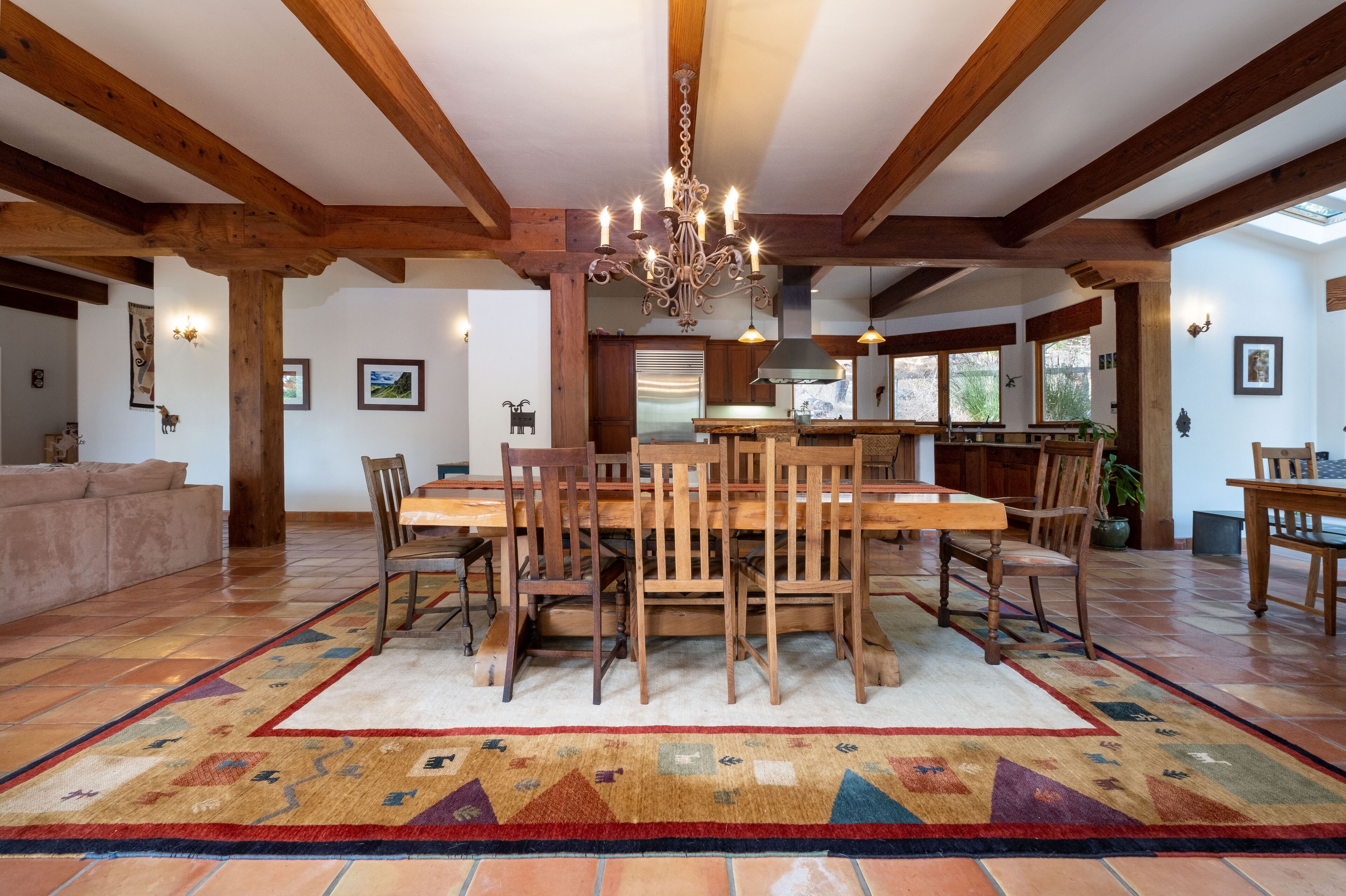 A spacious dining area with a large wooden table and chairs, surrounded by a patterned rug.