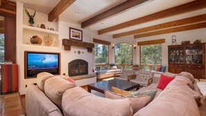 A spacious living room with a large beige sectional sofa, a fireplace, a television, and a wooden ceiling. - Custom Built Rental on Lodge Hill! Stunning Home in a Peaceful Neighborhood! (Cambria)