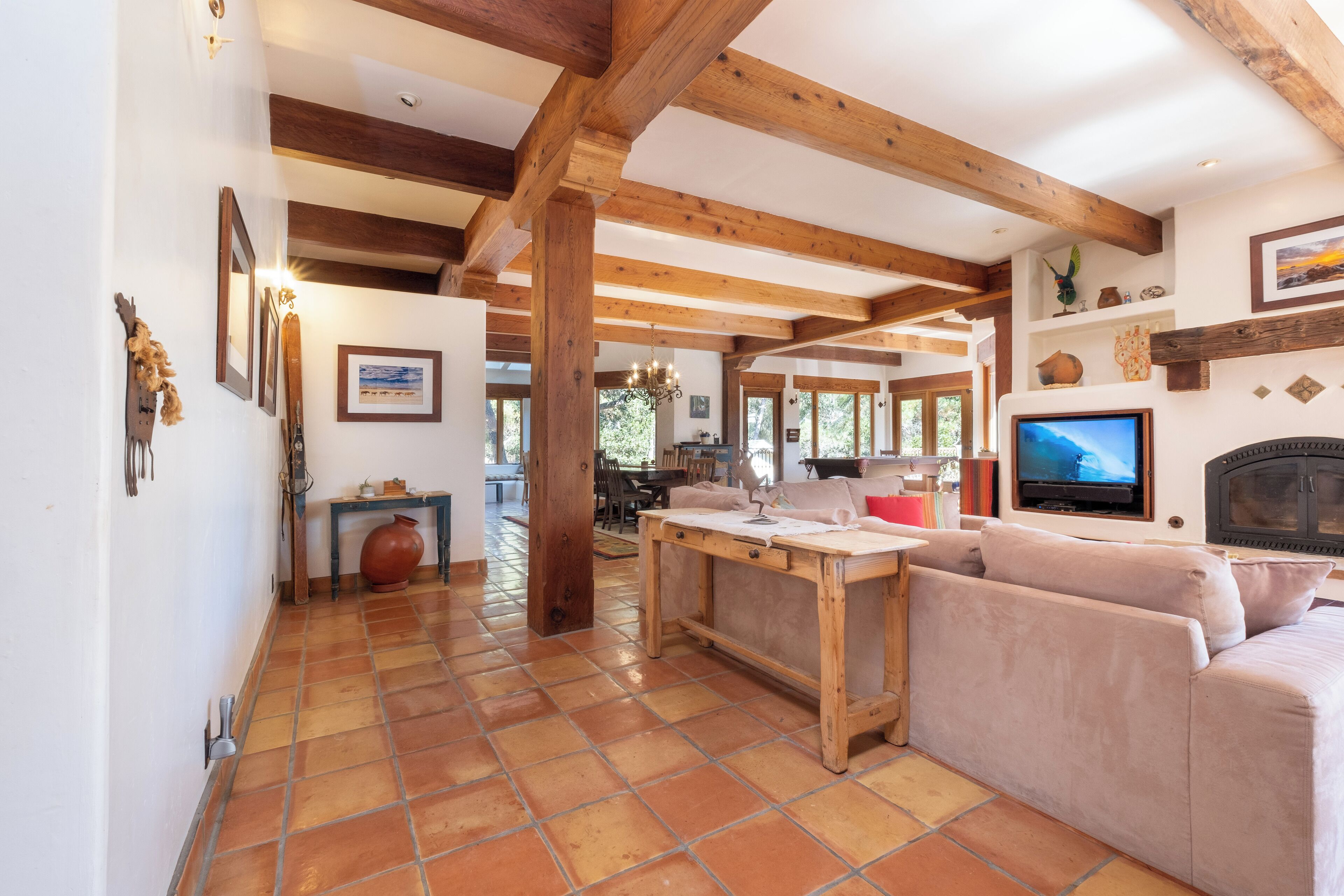 A spacious living area with a wooden ceiling, a large window, a sofa, and a television.
