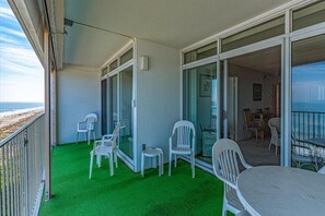 Enjoy the beach view from this balcony with a green artificial turf floor and comfortable seating area.
