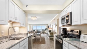 A modern kitchen with white cabinetry, a built-in microwave, and a coffee maker.