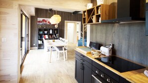 Une cuisine moderne avec un coin repas, des meubles en bois et un four encastré.