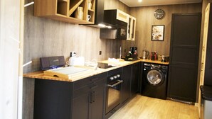 Une cuisine compacte avec des meubles en bois, un four encastré, un four à micro-ondes et un lave-linge.
