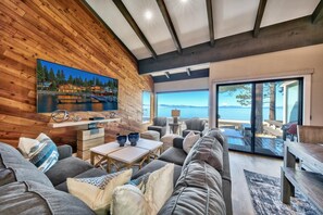 A modern living room with a large TV, comfortable seating, and a scenic view of the water. - Stunning Lakefront Near Heavenly LLV611 (South Lake Tahoe)