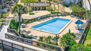 Un hotel con piscina, tumbonas y palmeras.