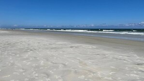 Una playa extensa con cielo despejado y mar tranquilo.
