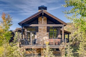 Una casa moderna con fachada de piedra, ventanas amplias y una terraza.