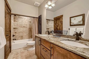 Une salle de bain avec une baignoire, deux lavabos, une douche, des meubles en bois, un porte-serviettes et un miroir.