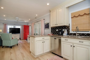 Enjoy cooking in this well-equipped kitchen with dishwasher and stainless steel sink, adjacent to a cozy living area with a flat-screen TV.