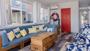 A room with a blue sofa, wooden chest, and a red door. - Pet Friendly Cottage Minutes from the KB Pier (Kure Beach)