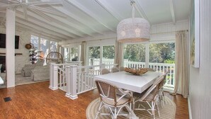 A spacious room with a large dining table surrounded by wicker chairs, a white ceiling fan, and a hanging light fixture. - "Driftwood" in S. Forest Beach! (Hilton Head Island)
