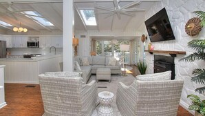 A spacious living area with a sofa, two armchairs, and a coffee table. A fireplace is visible on the right, and a television is mounted on the wall. - "Driftwood" in S. Forest Beach! (Hilton Head Island)