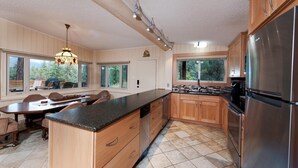 Une cuisine moderne avec des meubles en bois, un réfrigérateur en acier inoxydable et un coin repas comprenant une table et des chaises.