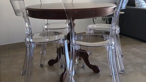 A dining table with clear chairs and a wooden top, surrounded by two framed posters on the wall. - Azurie Sea View Apartment (juan les pins)