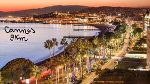 A coastal cityscape with a beach, palm trees, and a bridge. - Azurie Sea View Apartment (juan les pins)