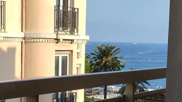 A table with a lamp on a balcony overlooking a coastal view. - Azurie Sea View Apartment (juan les pins)