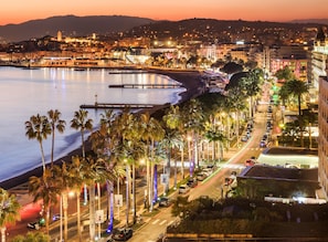 A coastal cityscape with a beach, palm trees, and a bridge. - Azurie Sea View Apartment (juan les pins)