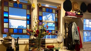Een keuken met een wit kastje, een vaas met bloemen en een raam met glas-in-lood.